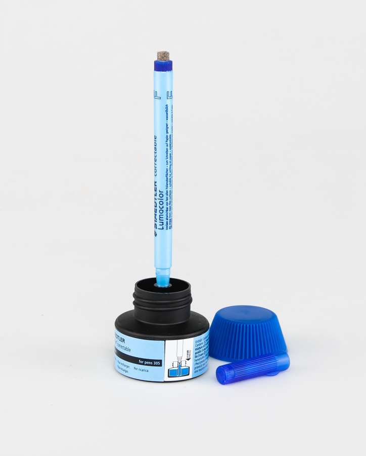 Erasable pen sticking upright in blue ink refill station