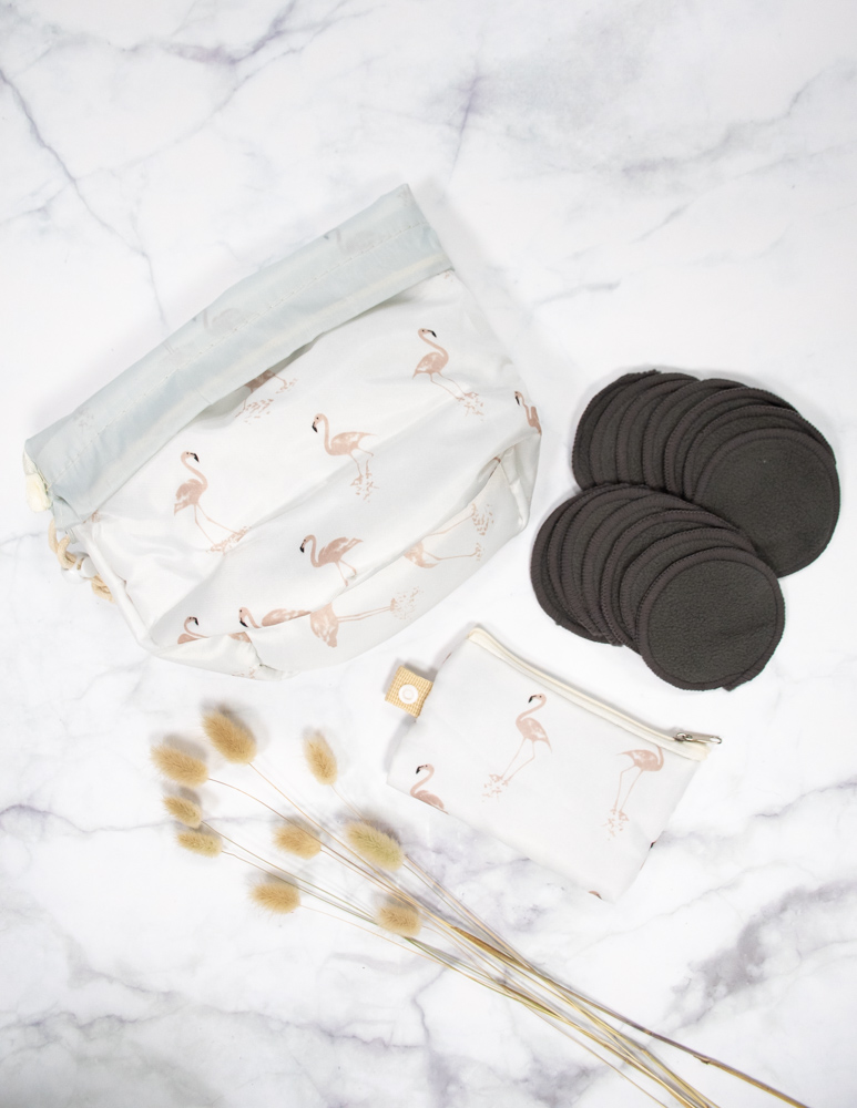 Set of dark-grey bamboo reusable make-up pads next to two bags on a marble background