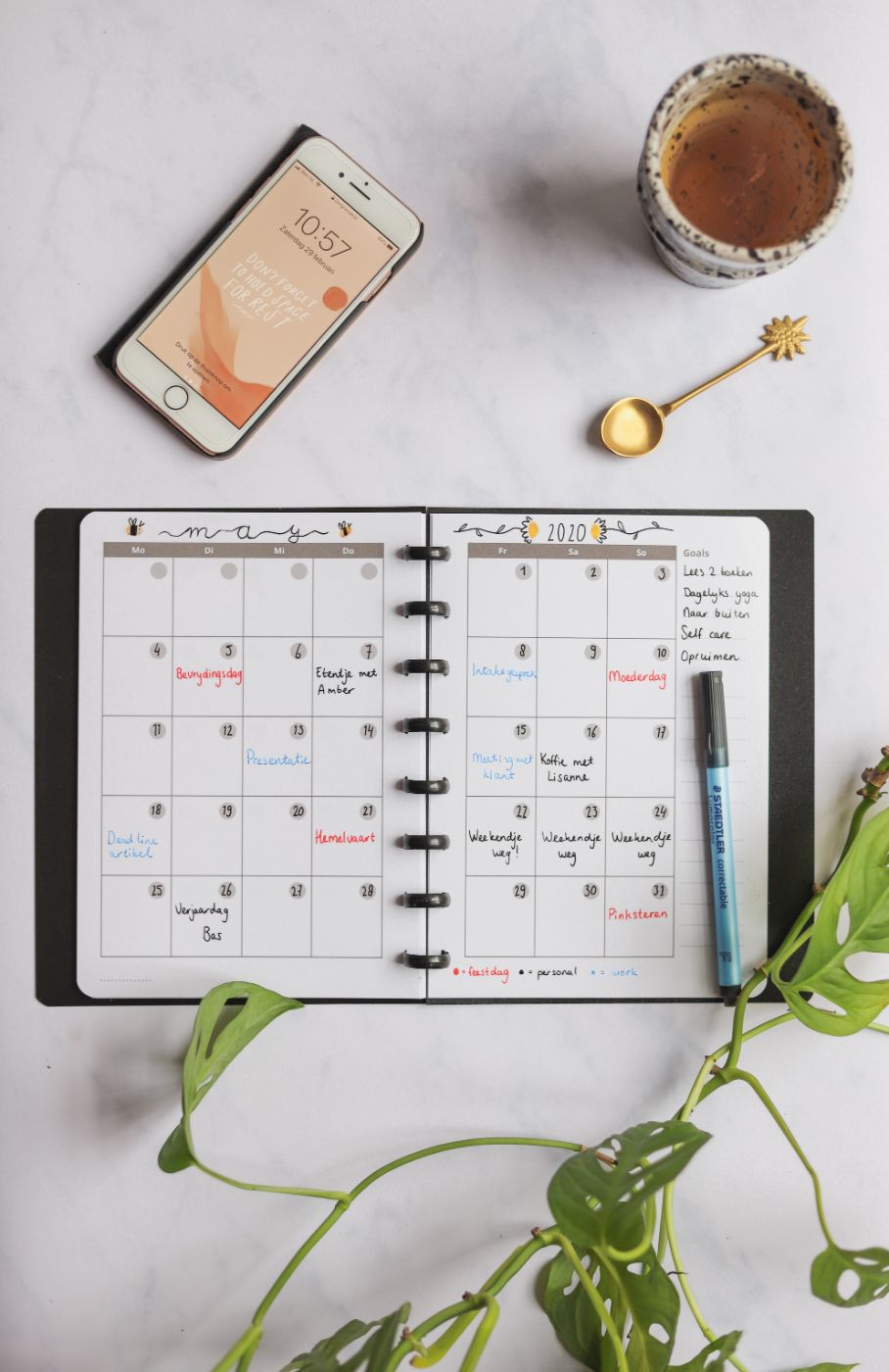 Vertical erasable weekly calendar next to assorted items on marble background